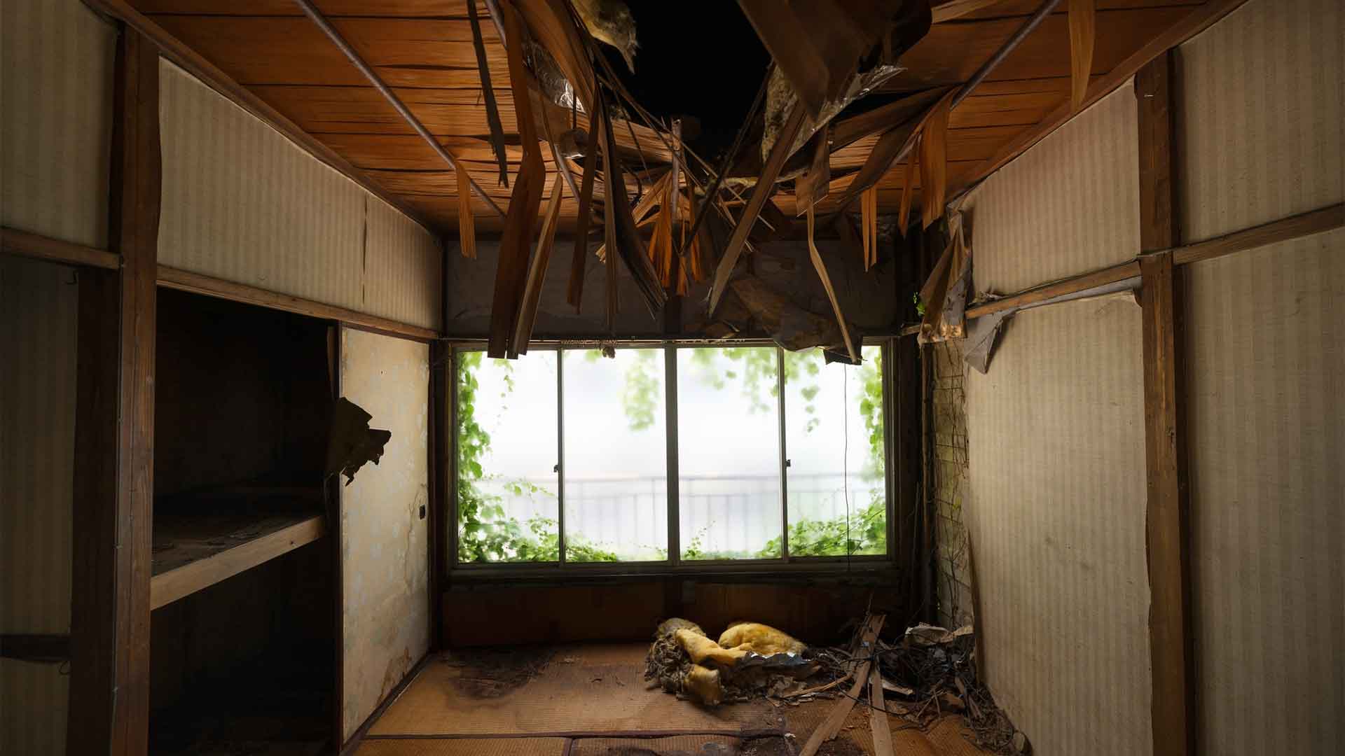 haunted-house-cluttered-interior-background Abandoned room with large hole in ceiling, wooden walls and beams, and yellow stuffed on floor.